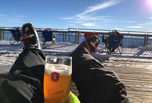 A skier drinking a weizen on a sunny chair at the Diedamskopf.
