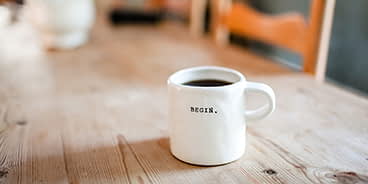 An image a filter coffee served in a white mug on a table.